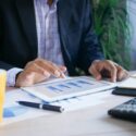 A man sitting at a table working on data analysis from his Higher Education Marketing Research Campaigns - Search Influence